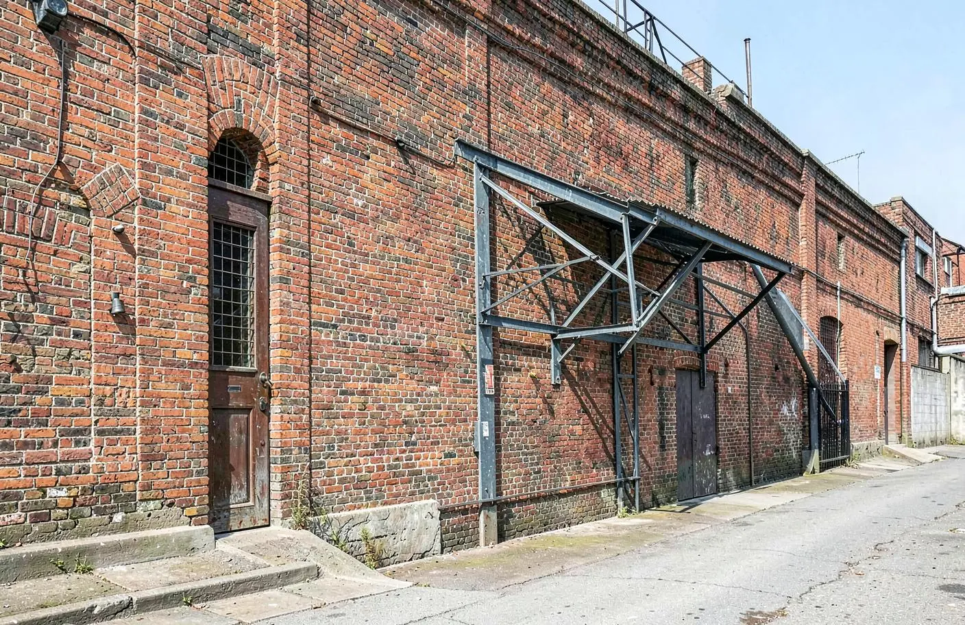 Bâtiment industriel ancien en brique avec une structure métallique adaptée à la façade