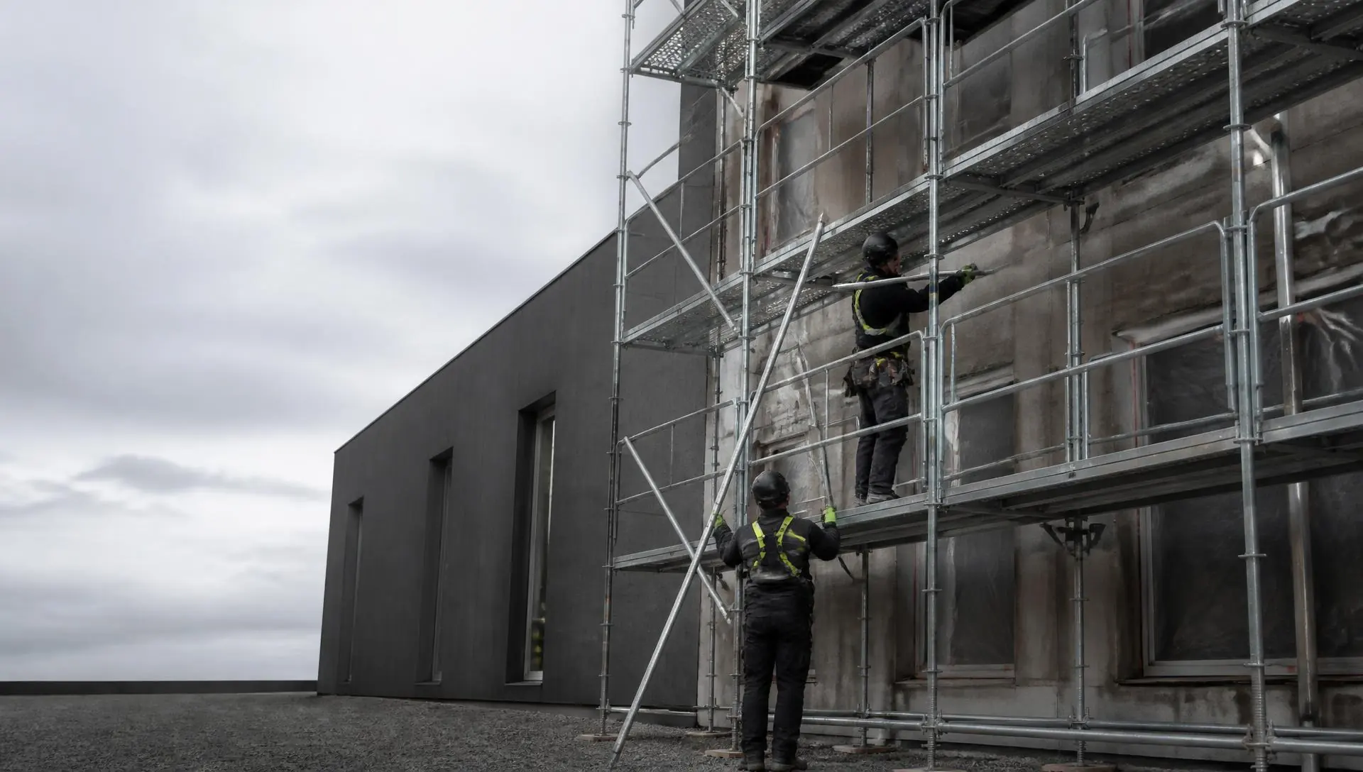 Deux professionnels assemblant un échafaudage sur un bâtiment